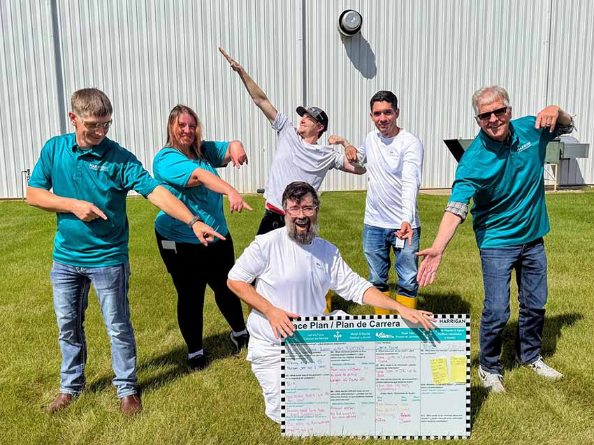 Harrigan team standing behind their Race Plan sign